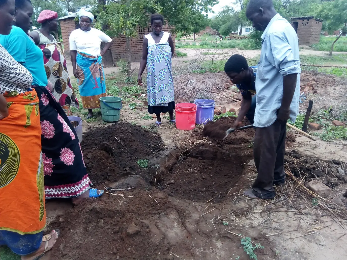 Adults gathered around a prepared soil and organic-material demonstration area