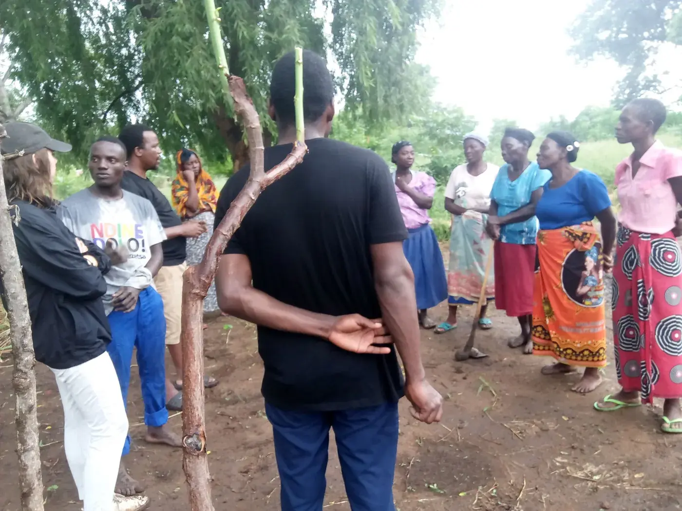 A facilitator listening as women farmers discuss agricultural priorities in a community field