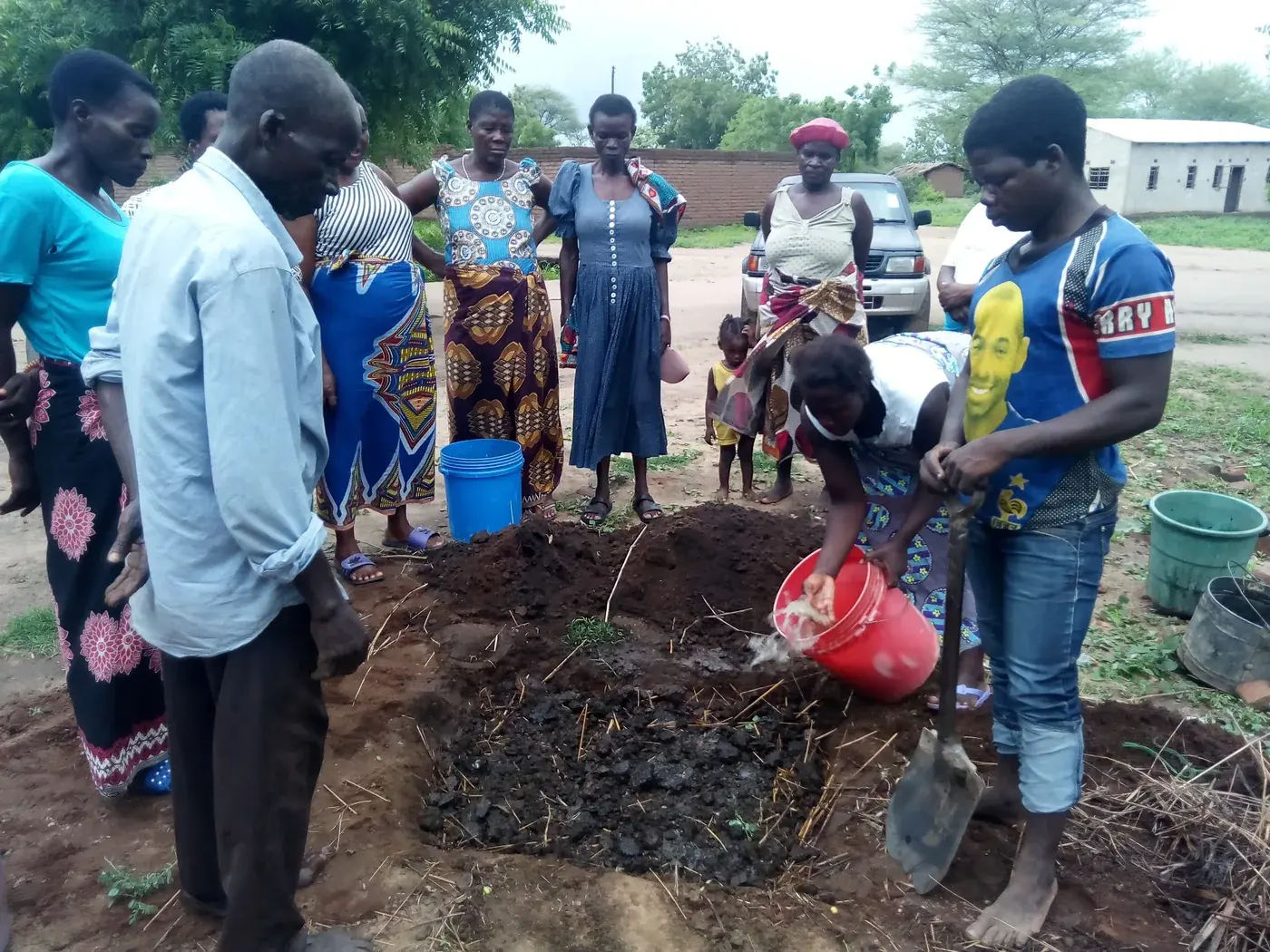 Community participants demonstrating compost and soil-improvement practices outdoors
