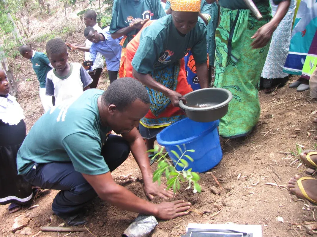 Community members and a SURCOD facilitator planting a tree