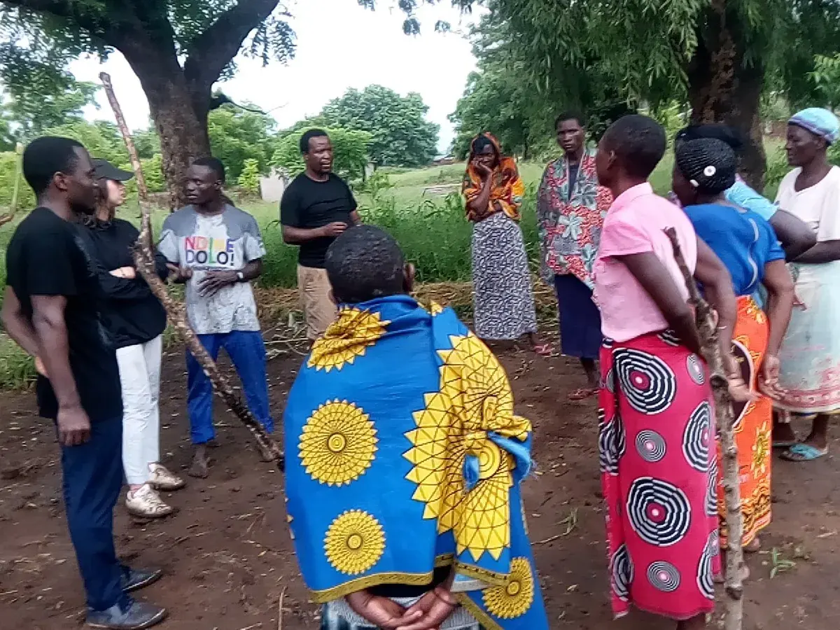 Community members and facilitators discussing farming practices in a cultivated field
