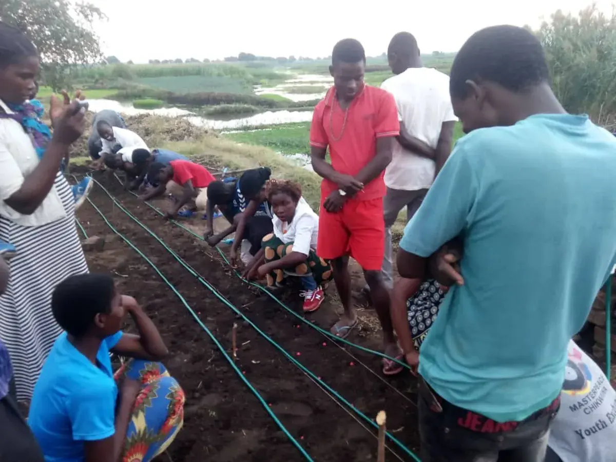 Community participants learning how to install drip irrigation lines in a demonstration garden