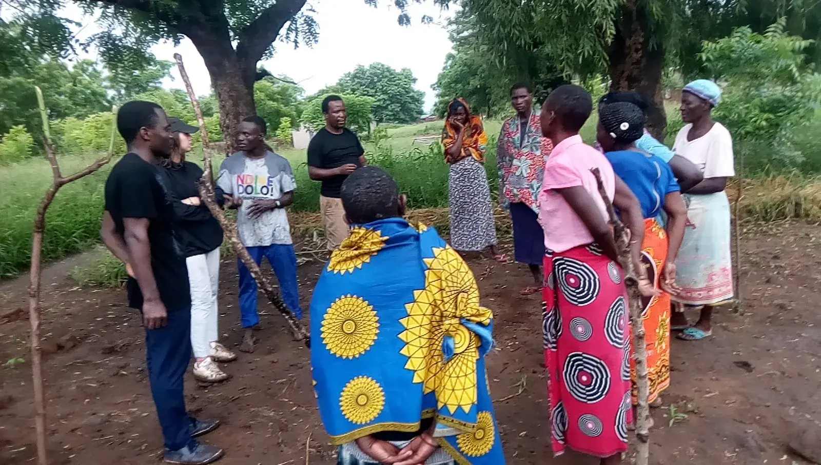 Women farmers and facilitators discussing local agricultural priorities beneath trees