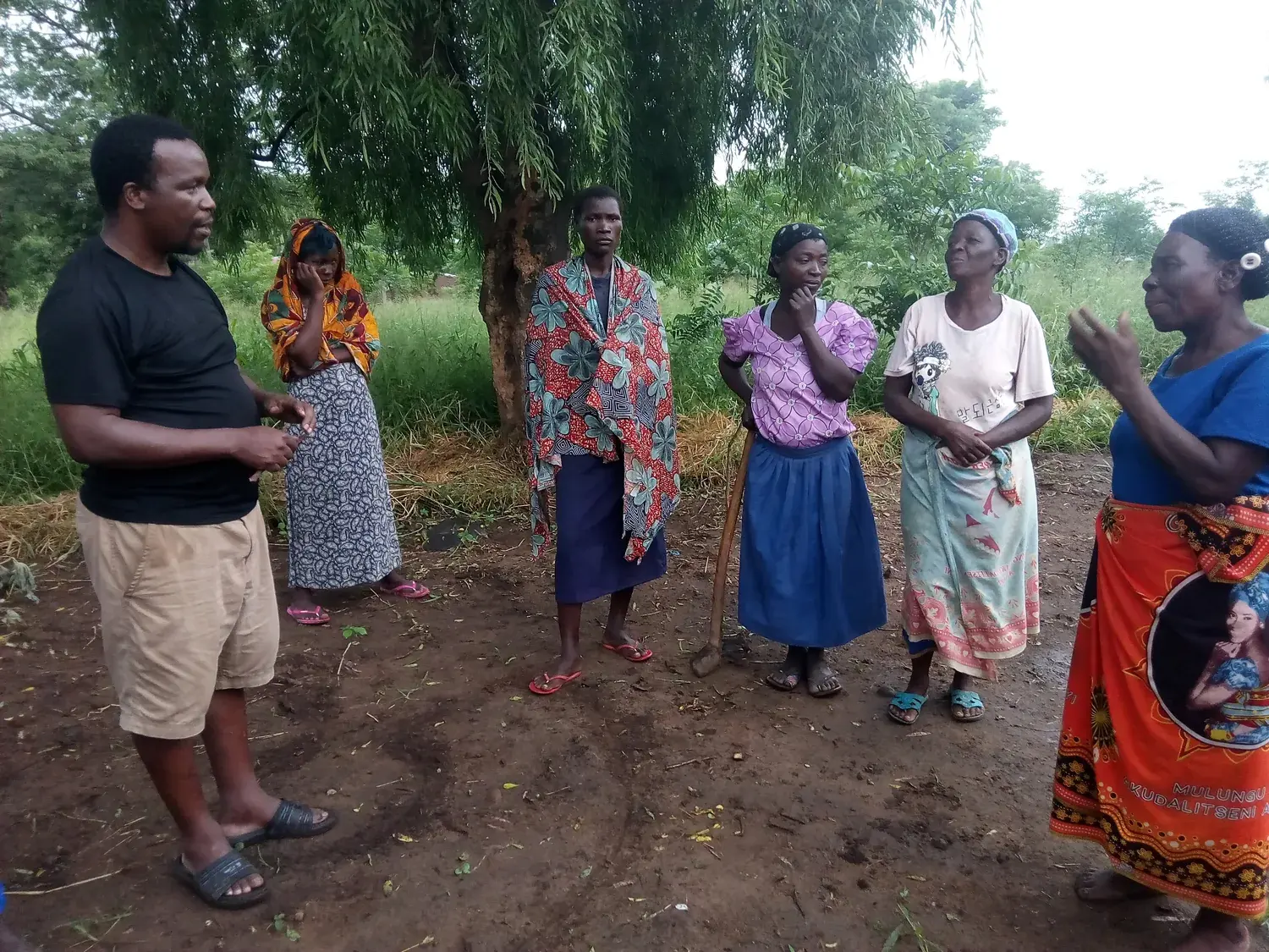 Community members and a SURCOD facilitator discussing local agricultural priorities outdoors