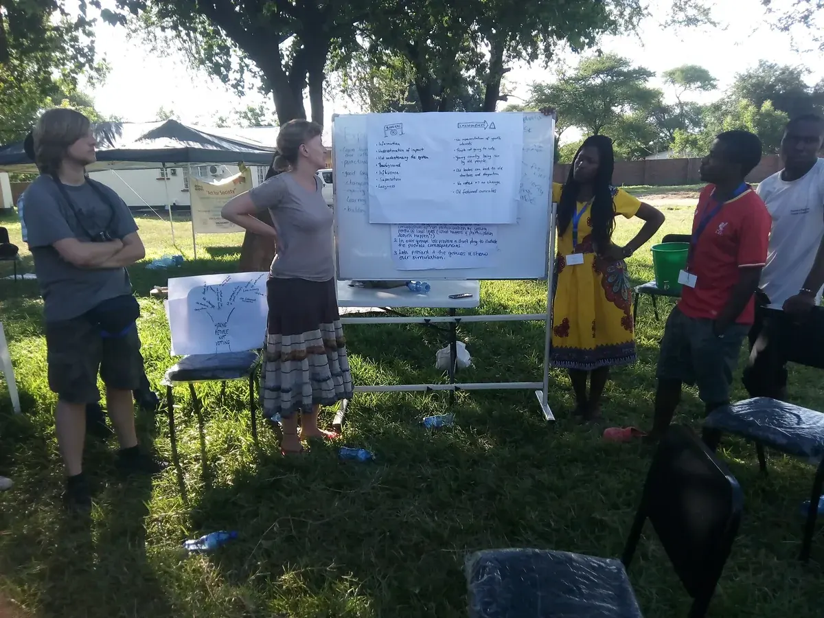 Young adults presenting ideas beside a community workshop display