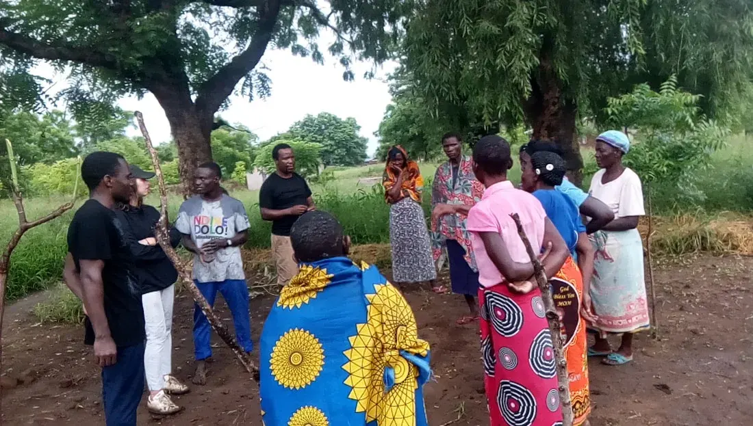 Community members and facilitators talking outdoors beside a garden